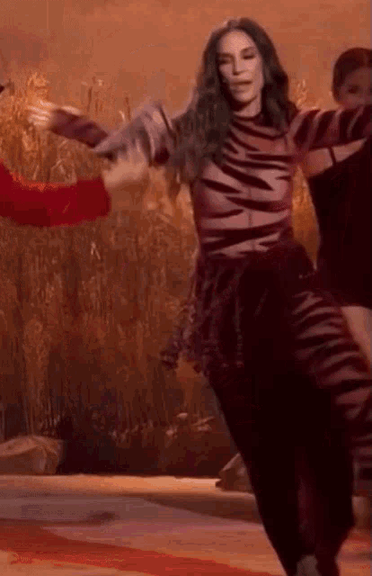 a woman in a zebra print jumpsuit is dancing on a stage .