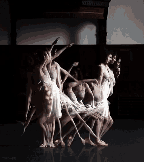 a group of dancers are dancing in a dark room