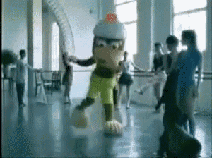a group of people are dancing in a room with a mascot in the middle