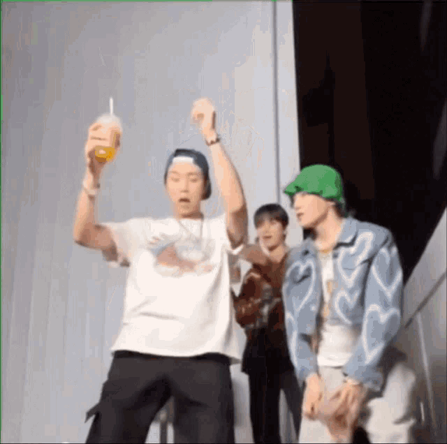 a group of young men are standing next to each other and one is holding a drink in his hand .