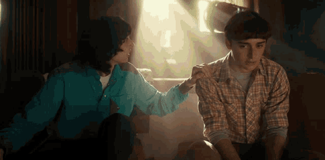 a man and a woman are sitting on a couch with the sun shining through the window