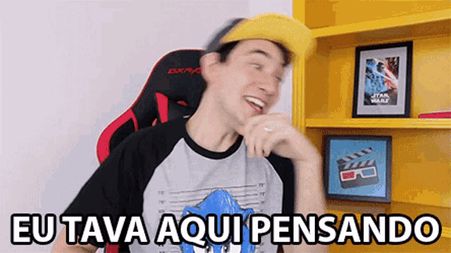 a man sitting in a chair with the words eu tava aqui pensando on the bottom