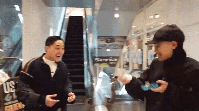 two men are standing in front of an escalator and a sign that says seria