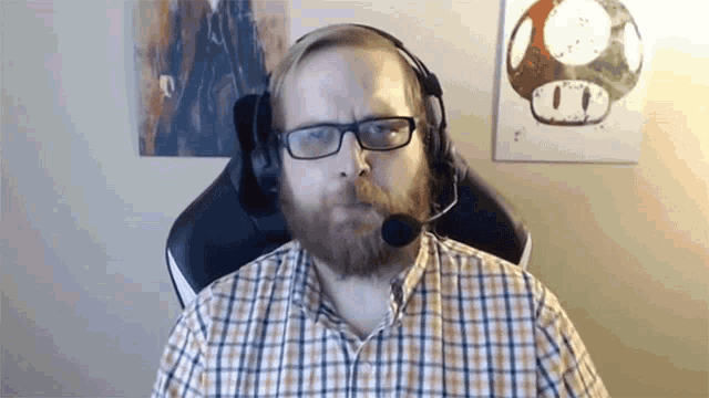 a man with a beard and glasses is wearing a headset .