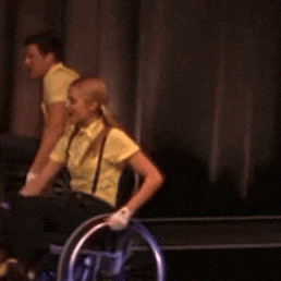 a woman in a yellow shirt is sitting in a wheelchair