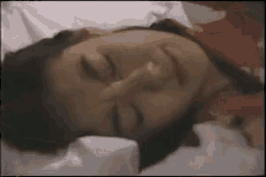 a woman is laying on a bed with her eyes closed and her hand on her face .