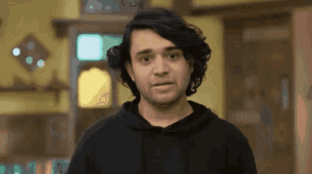 a man in a black hoodie is making a face