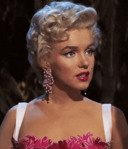 a close up of a woman wearing a pink feathered dress and earrings