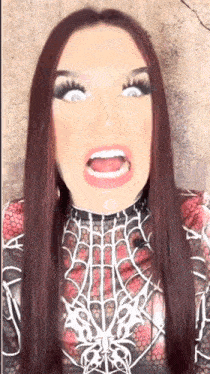 a woman with long red hair is wearing a spiderman costume and making a funny face