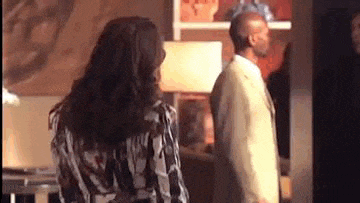 a man in a suit and a woman in a dress are standing next to each other in a living room .