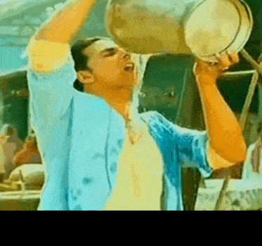 a man is drinking water from a bucket .