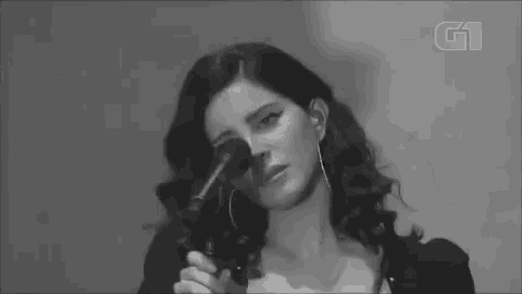 a black and white photo of a woman holding a microphone and covering her eyes .