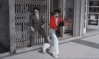 a man in a suit and tie is dancing in front of a building
