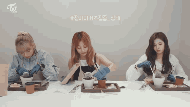 three women sitting at a table with a twice logo on the bottom right