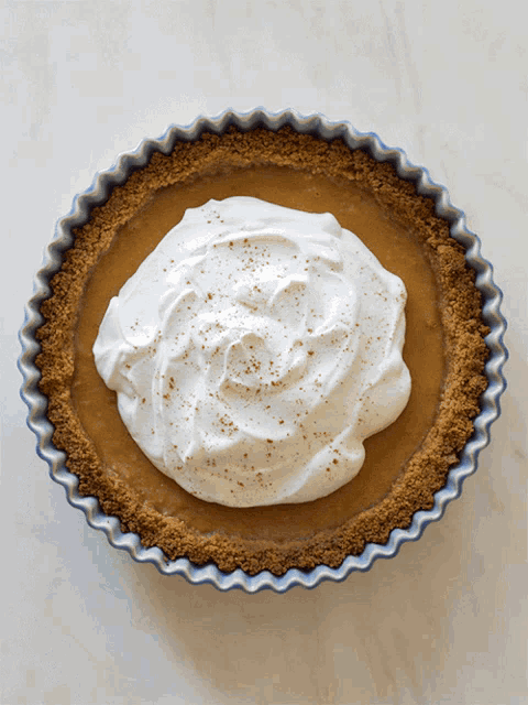 a pie with whipped cream and cinnamon sprinkles on top