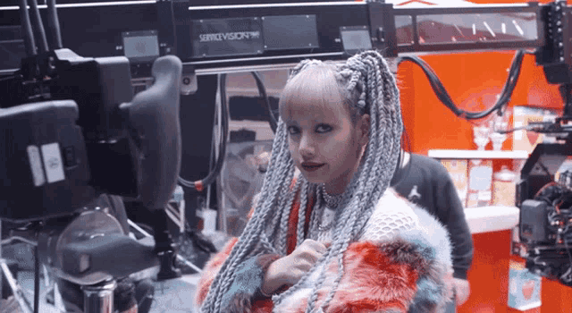 a woman in a fur coat stands in front of a servicevision machine