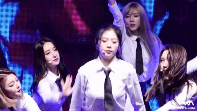 a group of women are dancing on a stage with a website in the corner that says m.com