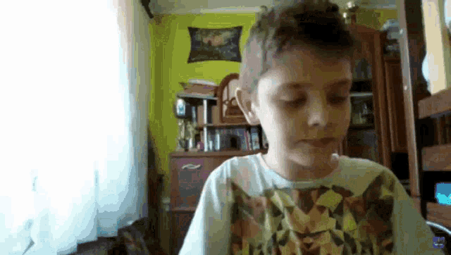 a young boy is sitting in a living room with his eyes closed and his shirt on .