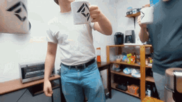 a man in a white shirt is drinking from a white mug with a black triangle on it
