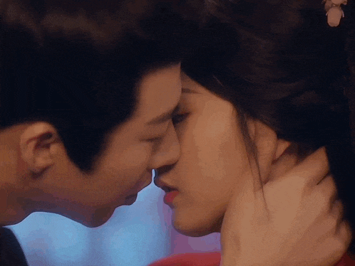 a man and a woman are kissing in front of a window .