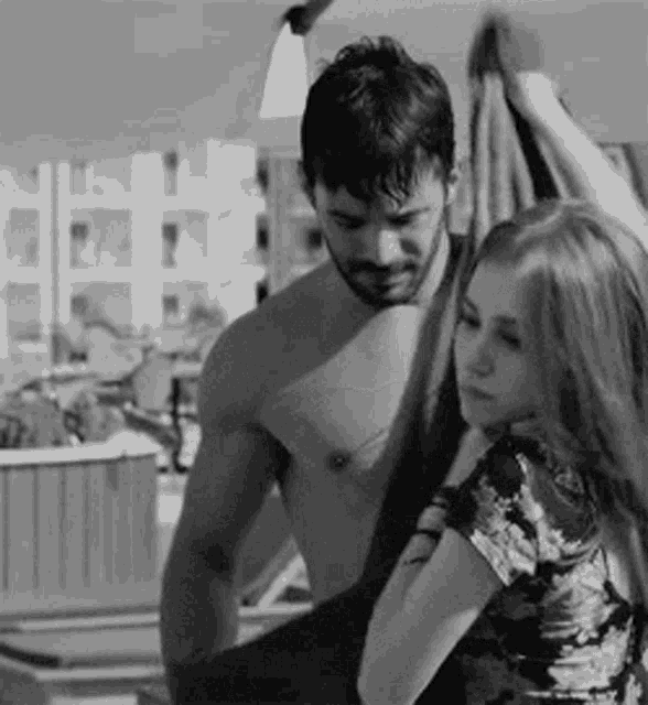 a black and white photo of a shirtless man and a woman .
