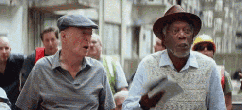 two older men in hats are standing next to each other on a street .