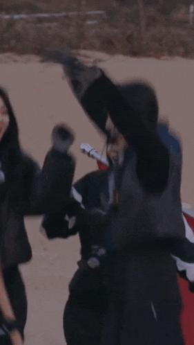 a woman is fighting another woman on a beach with a red kite .