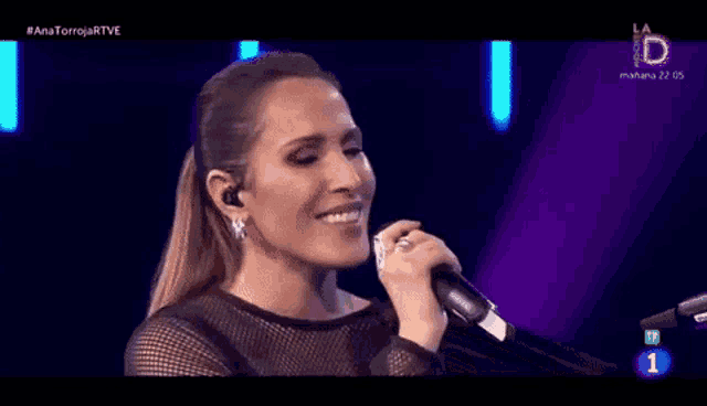a woman singing into a microphone with the number 1 on the bottom left