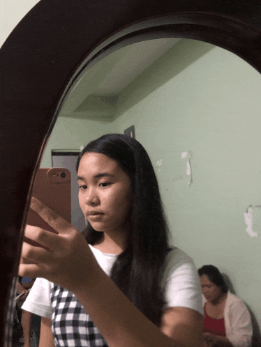 a girl taking a selfie in a mirror with her phone
