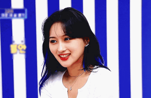 a woman with blue hair is smiling in front of a striped wall