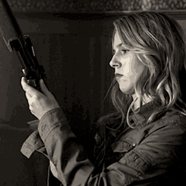 a woman is holding a shotgun in her right hand