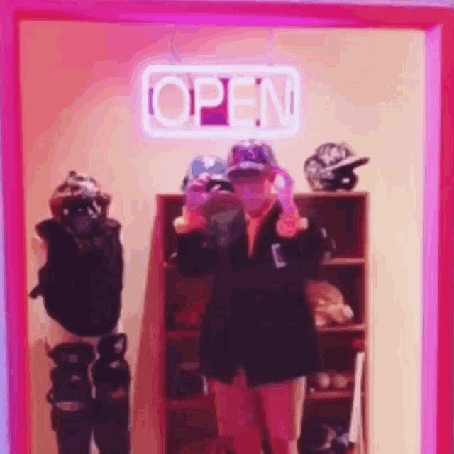 a woman is standing in front of a neon sign that says `` open '' .