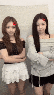 two girls are standing next to each other with their arms crossed and one has a red sticker on her face