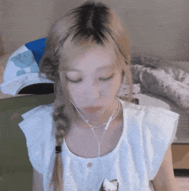a woman wearing headphones and a braided ponytail looks down at something