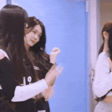three girls are standing next to each other in front of a blue door .