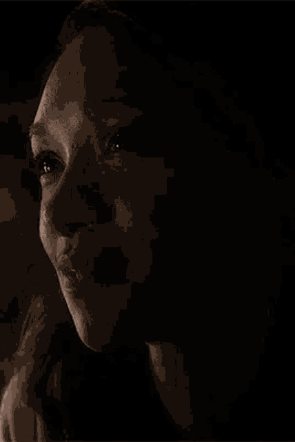 a close up of a woman 's face in the dark smiling .