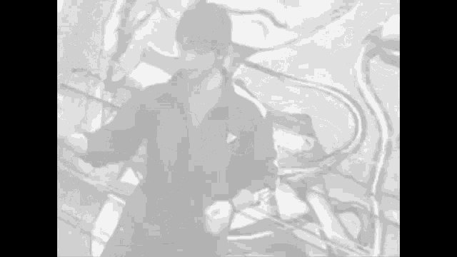 a black and white photo of a man dancing in front of a mural .