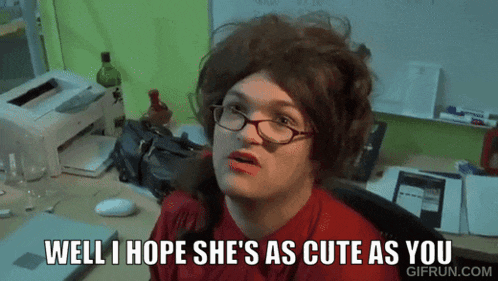 a woman wearing glasses is sitting at a desk and says well i hope she 's as cute as you