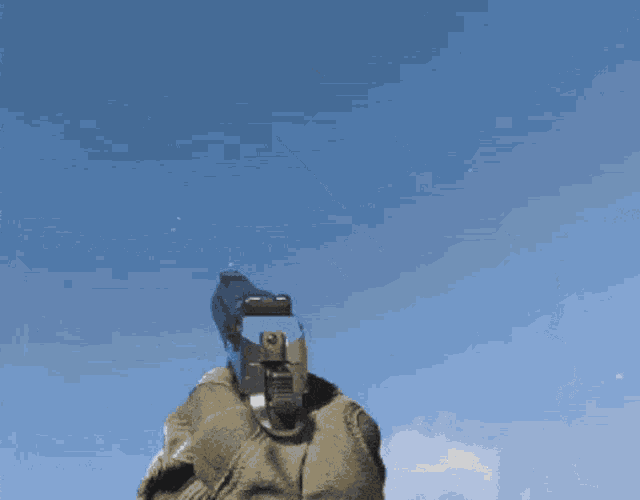 a person is holding a gun in their hand with a blue sky in the background