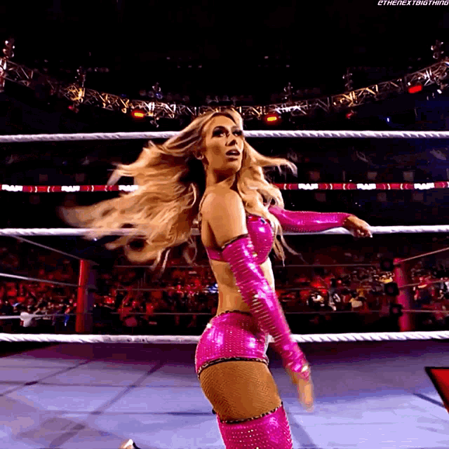 a woman in a pink wrestling outfit is standing in a ring