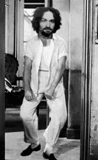 a man with a beard is standing in front of a mirror .