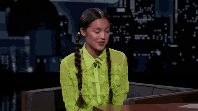 a woman in a neon green shirt is sitting in a chair .