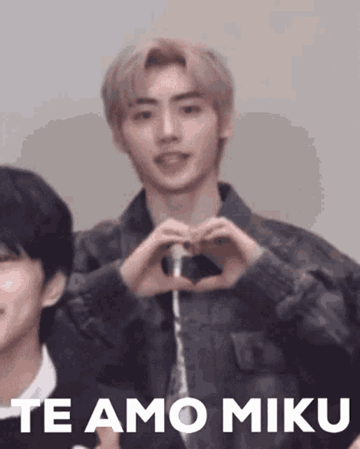 a man is making a heart shape with his hands and the words `` te amo miku '' .