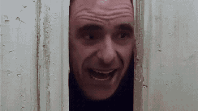 a man is peeking out of a doorway and making a face .