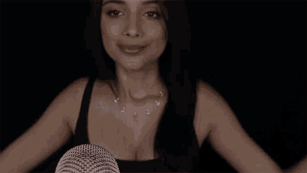 a woman is sitting in front of a microphone with her hands up .