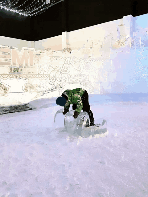 a person in a green jacket is playing in the snow in front of a sign that says kemi