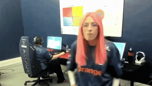a woman with pink hair wears a shirt that says orange