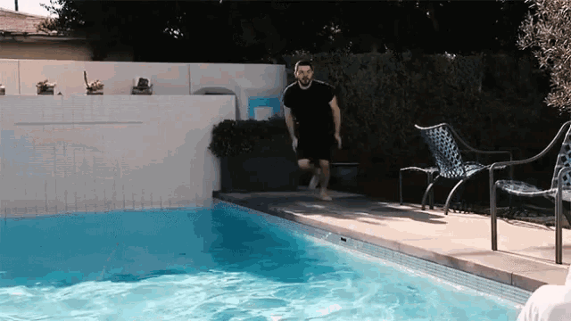 a man in a black shirt is running into a pool