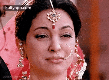 a woman wearing a nose ring and a maang tikka is crying .