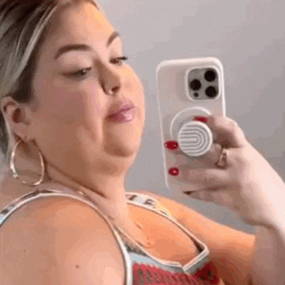a woman is taking a selfie with her cell phone in front of a mirror .